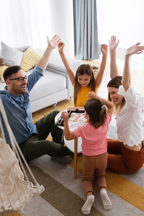 Happy Young Parents and Children Having Fun, Playing Board Game at Home