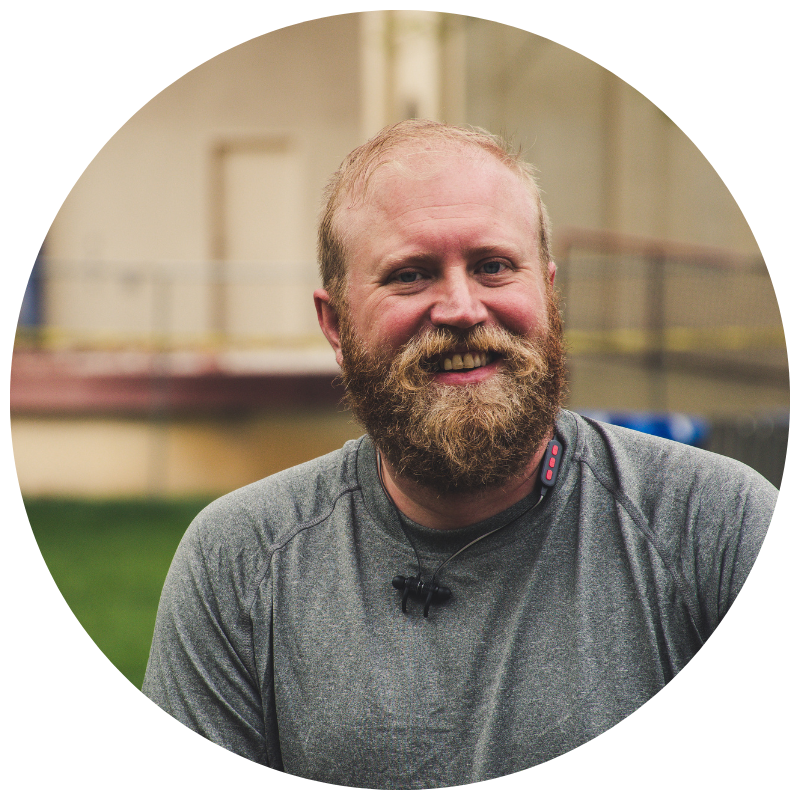Man in a grey shirt with a red beard smiling at the camera