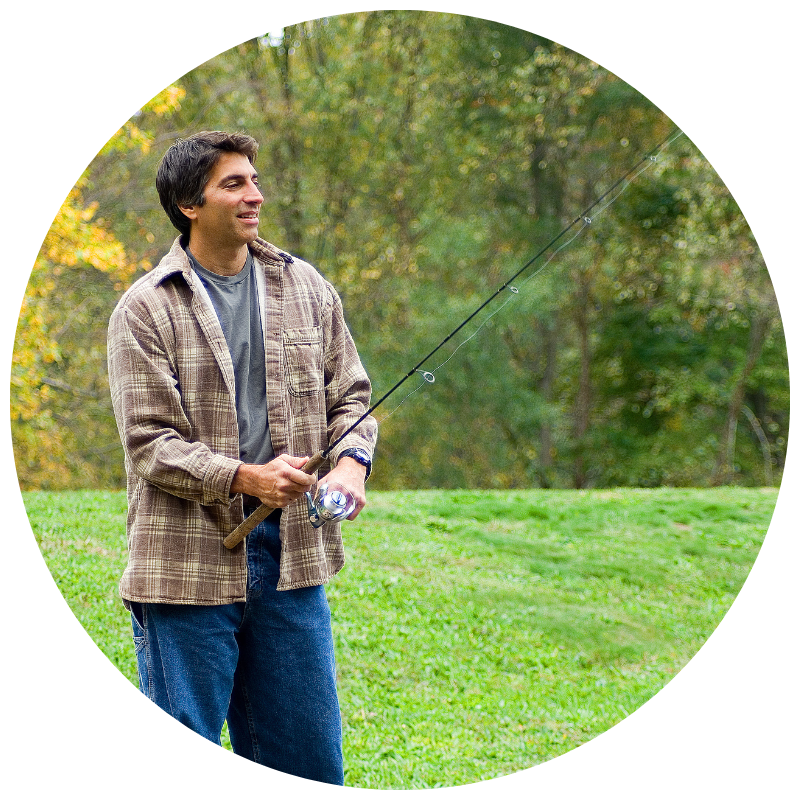 Man in a tan and brown flannel outside in the fall holding a fishing rod